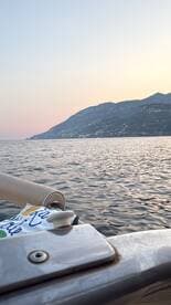 A serene view from a boat at sunset, showcasing the calm waters and distant mountains — perfect for peaceful evening cruises.