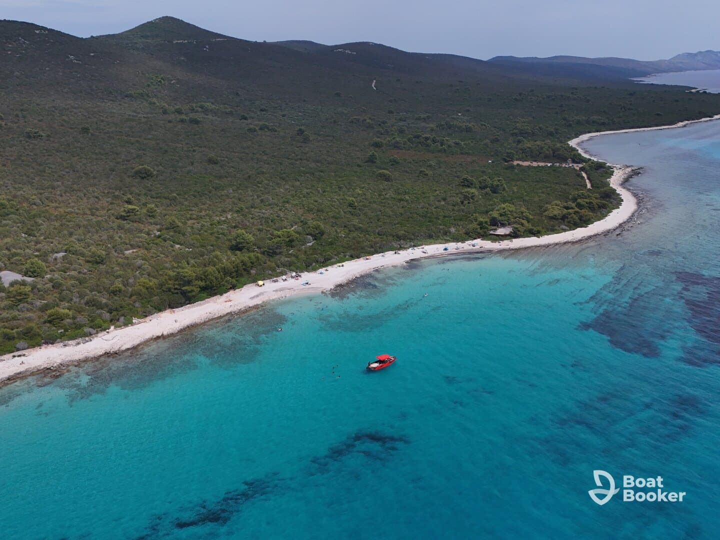 A stunning aerial view of a secluded beach with turquoise waters and a vibrant red boat anchored nearby, perfect for showcasing the beauty of island destinations.