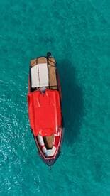 A stunning aerial view of a sleek red speedboat gliding over crystal-clear turquoise waters, perfect for thrilling adventures on the sea.