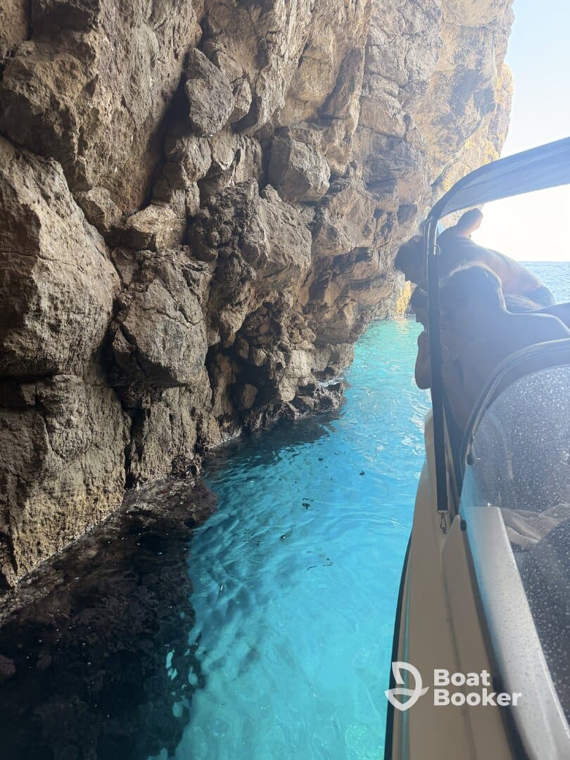 A group leans over the side of a boat to admire the stunning turquoise waters and rocky cave formations — a perfect moment of exploration on the water.