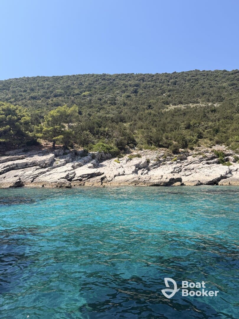 A stunning view of a rocky coastline with lush greenery and crystal-clear turquoise waters, perfect for showcasing the natural beauty of the area.