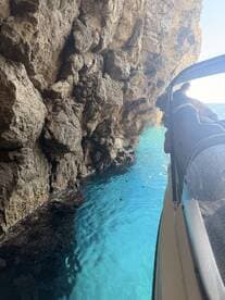A group leans over the side of a boat to admire the stunning turquoise waters and rocky cave formations — a perfect moment of exploration on the water.