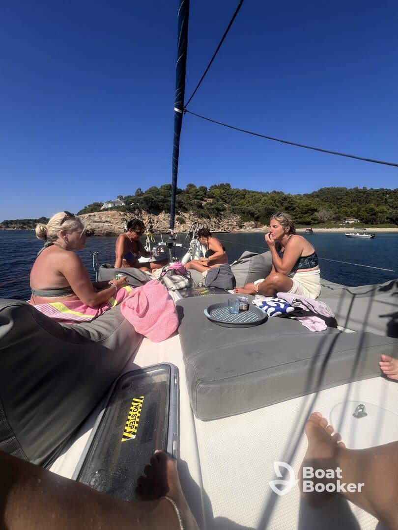 A group of friends enjoys a relaxing day on a sailboat, soaking up the sun and sharing drinks — perfect for a memorable getaway on the water.
