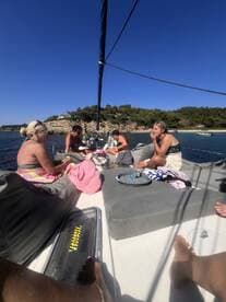 A group of friends enjoys a relaxing day on a sailboat, soaking up the sun and sharing drinks — perfect for a memorable getaway on the water.