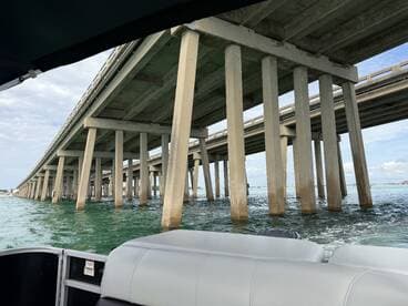 A view from a boat looking up at a bridge, showcasing the structural pillars above the water. The image lacks clarity and focus on the main subject.