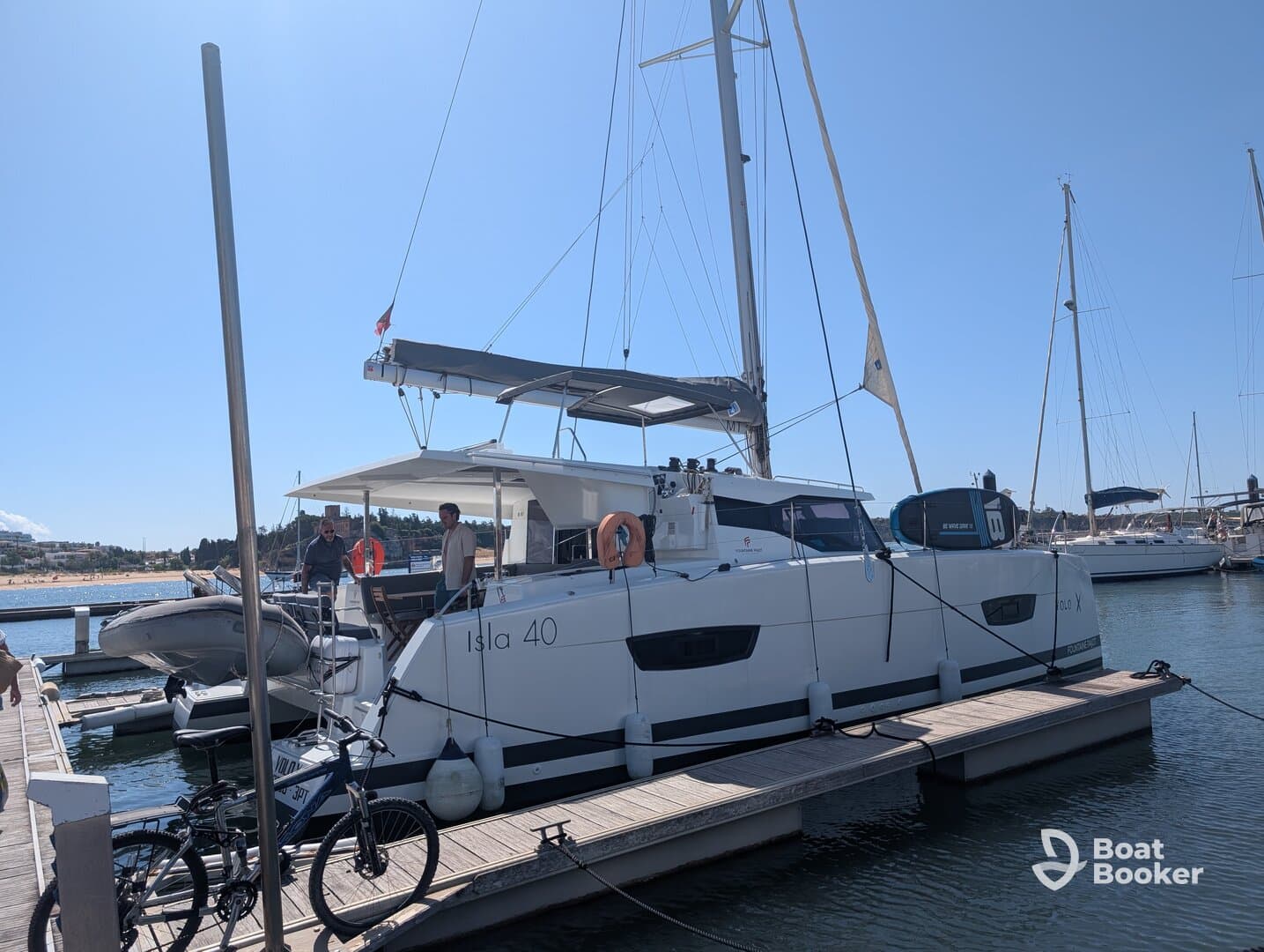 A catamaran named 'Isla 40' docked at the marina with people onboard, showcasing a perfect setting for sailing adventures.