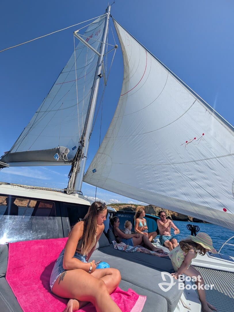 A lively group enjoys a day of sailing on a catamaran, relaxing on the deck with stunning views and good company.