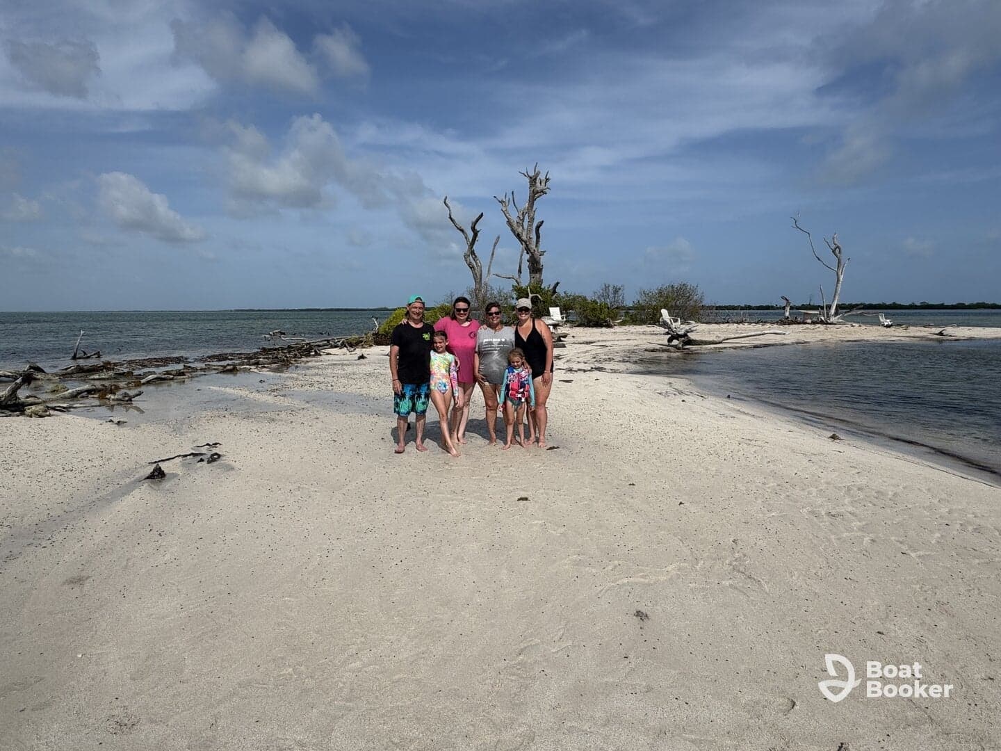 A joyful family poses together on a sandy beach, capturing a memorable moment during their sandbar adventure — perfect for family outings and beach fun.