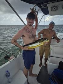 Two friends celebrate a successful fishing trip aboard a boat, showcasing their catch in the beautiful open water — a perfect moment for fishing enthusiasts.