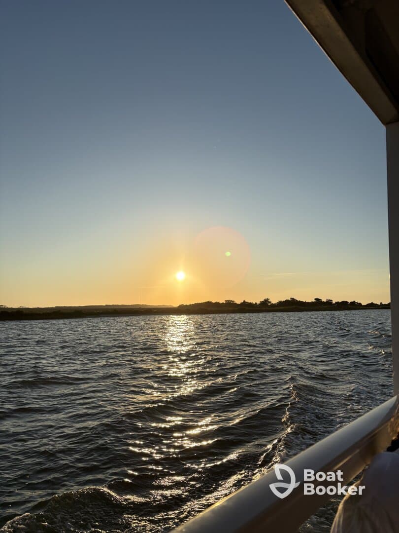 A serene sunset view over the water, captured from the deck of a boat, showcasing the tranquil beauty of evening cruises.