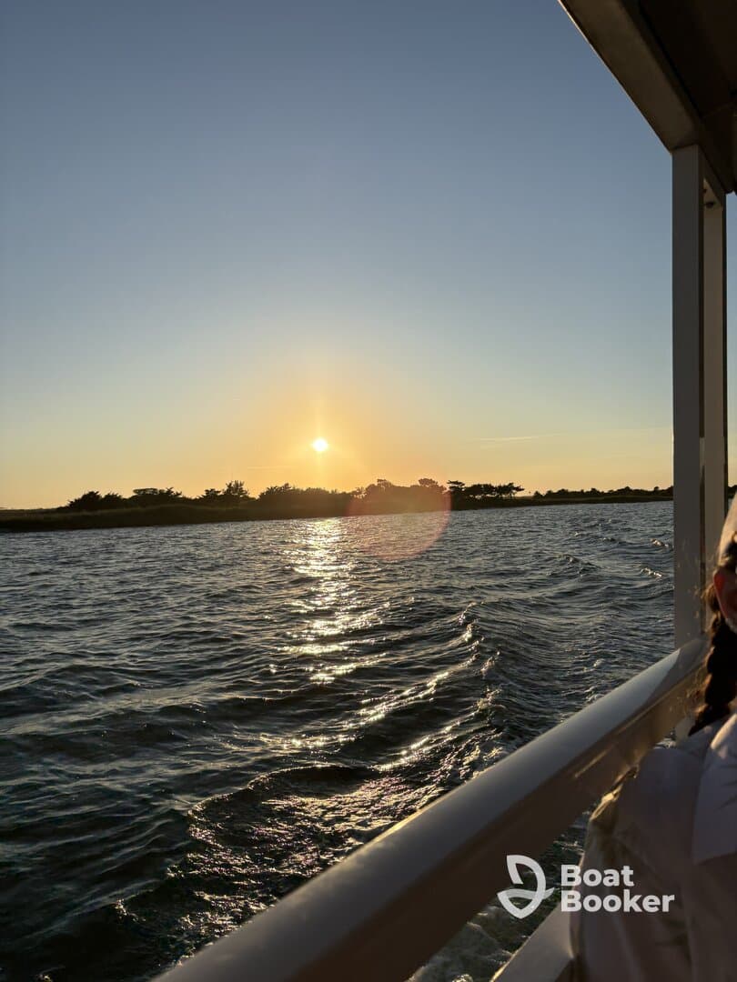 A stunning sunset view from a boat, capturing the shimmering water and silhouettes of trees — perfect for a serene evening cruise.