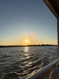 A serene sunset view over the water, captured from the deck of a boat, showcasing the tranquil beauty of evening cruises.