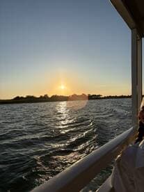 A stunning sunset view from a boat, capturing the shimmering water and silhouettes of trees — perfect for a serene evening cruise.