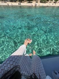 A guest enjoys a refreshing drink while relaxing by the crystal-clear waters, capturing the essence of a perfect beach day.