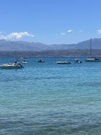 A picturesque view of various boats enjoying a sunny day on the water, set against a stunning mountainous backdrop — perfect for a day of exploration and relaxation.