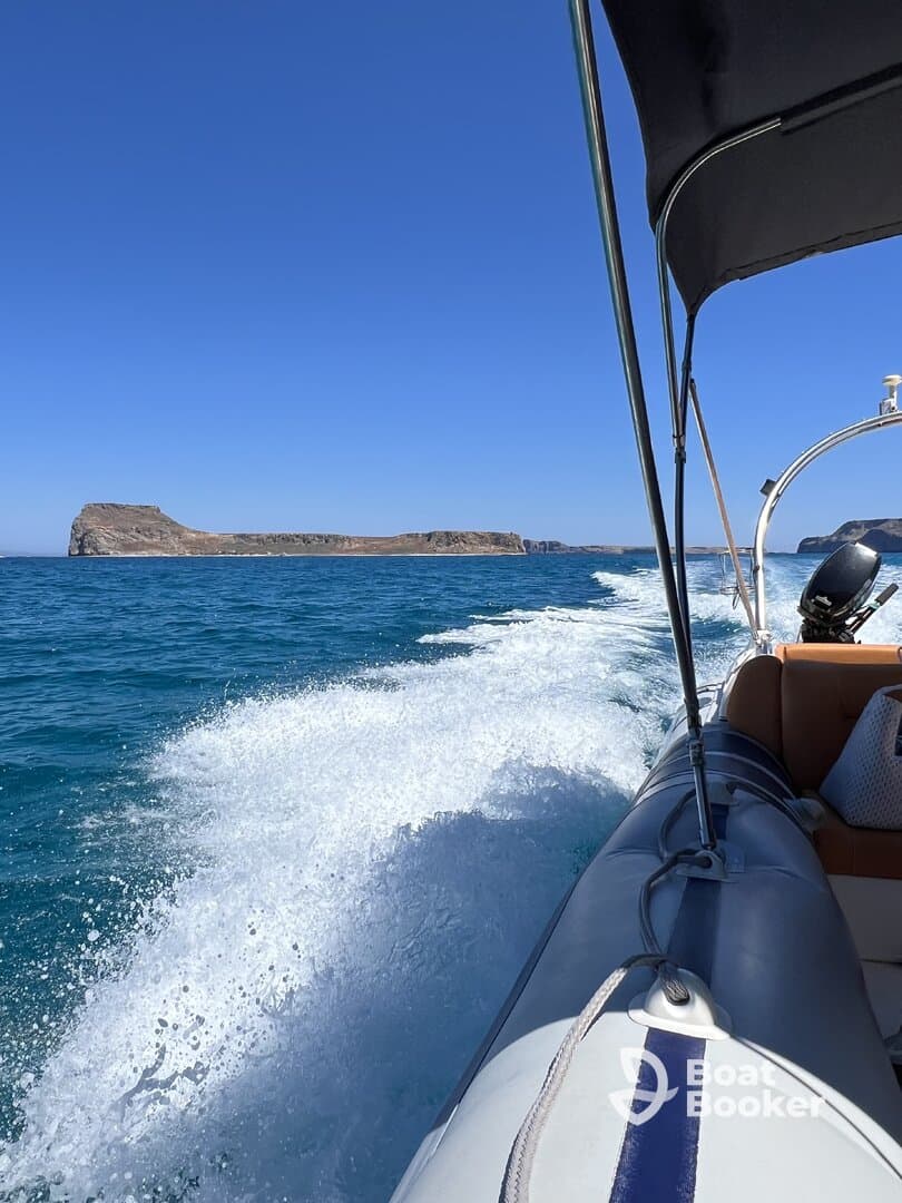 A scenic view from a boat cruising through clear blue waters, showcasing a distant island against a vibrant sky — perfect for adventure seekers and nature lovers.