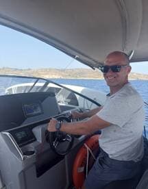A man confidently navigates the helm of a modern boat, showcasing the sleek interior and advanced controls — perfect for a day of adventure on the water.