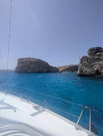 A stunning view of rocky cliffs and vibrant blue waters, showcasing the beauty of the coastline while cruising on a boat.