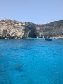 A stunning view of a coastal cave with crystal-clear blue waters, perfect for exploring and enjoying the natural beauty of the surroundings.