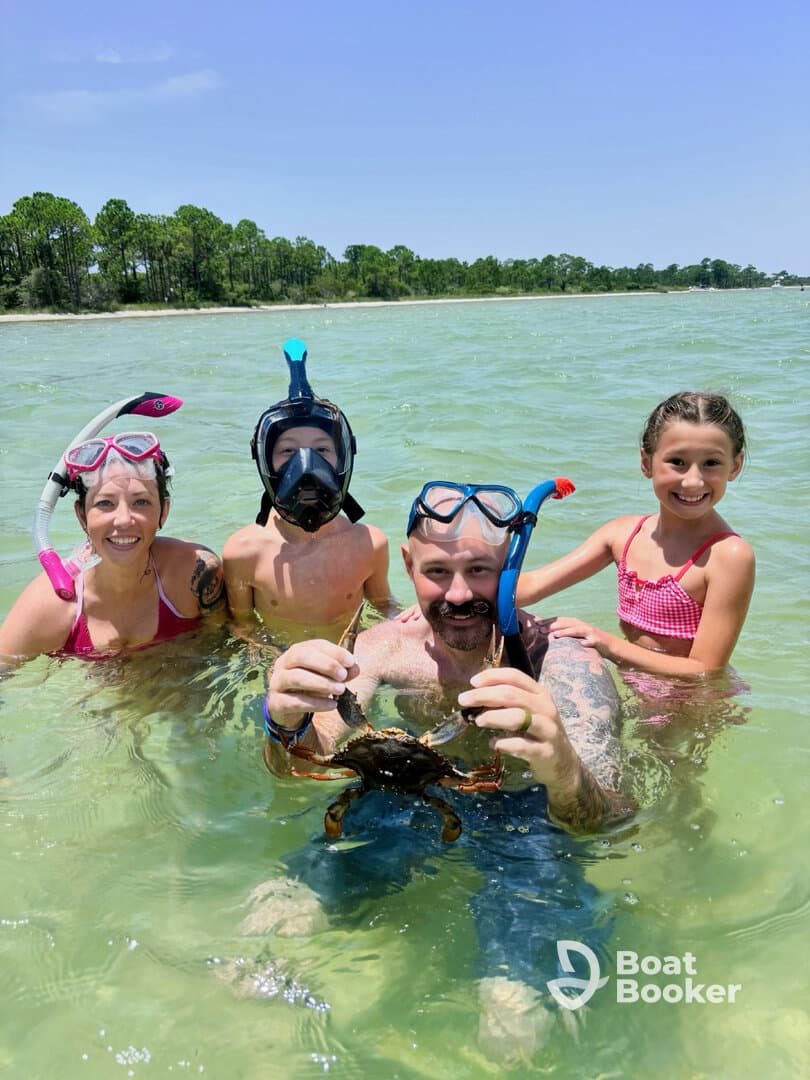 A family enjoys a fun snorkeling adventure, showcasing a crab caught in shallow waters — a perfect moment for wildlife interaction and family bonding.