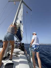 A group of friends actively sailing on a yacht, adjusting the sails while enjoying a beautiful day on the water — perfect for adventure seekers and sailing enthusiasts.