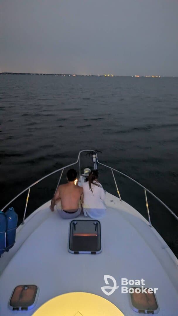 A couple enjoys a romantic evening on a boat, illuminated by soft lights against the backdrop of a serene night sea.