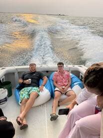 A group of friends relaxes on bean bags aboard a boat, enjoying drinks and the scenic water view — perfect for a fun day on the water.