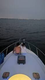 A couple enjoys a romantic evening on a boat, illuminated by soft lights against the backdrop of a serene night sea.