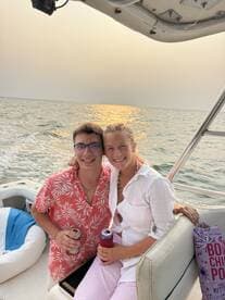 A happy couple enjoys drinks together on a boat at sunset, capturing a perfect moment of celebration on the water.