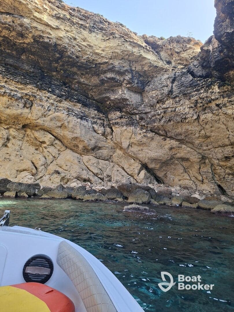 A scenic view of a boat near a rocky coastline, showcasing clear waters and natural rock formations — perfect for exploring hidden coves.