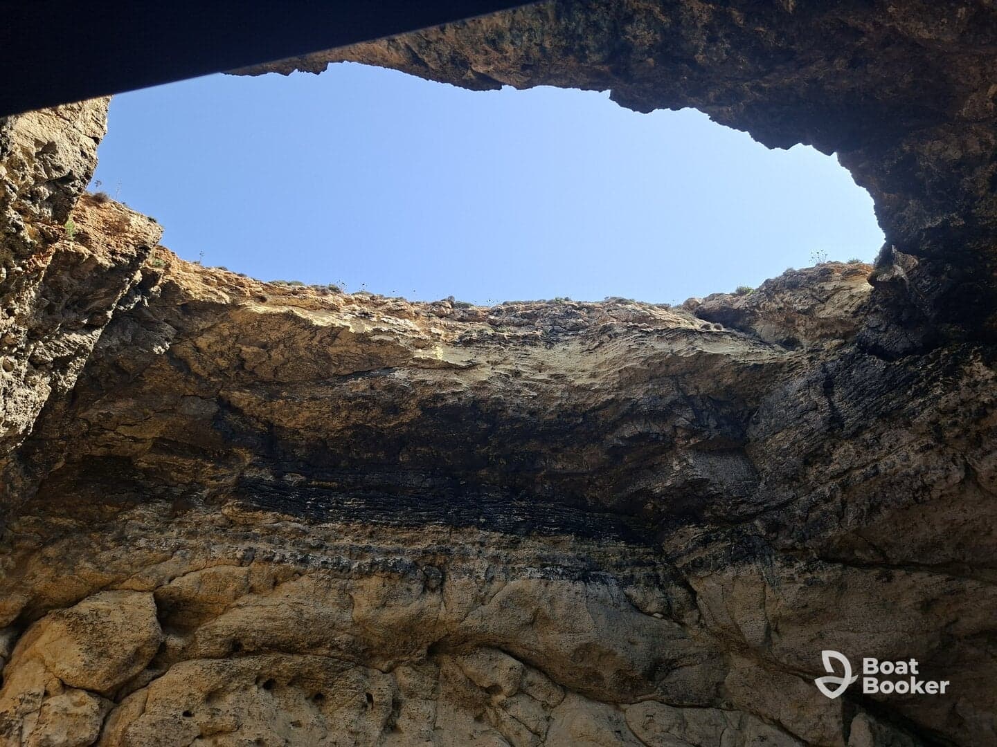 An unclear view of a rocky cave opening against a bright blue sky, lacking identifiable features or subjects.