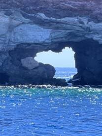 A stunning view of a natural rock arch along the coastline, showcasing the beauty of the ocean and surrounding landscape — perfect for scenic boat tours.