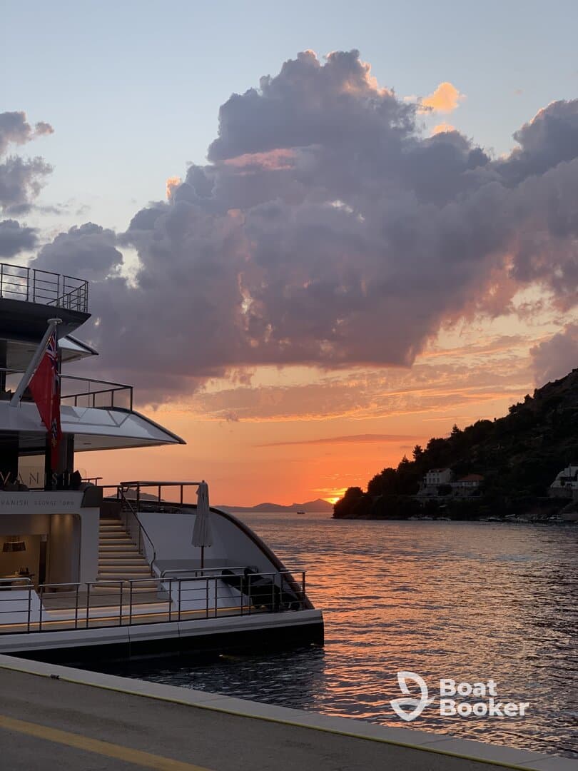 A stunning sunset view featuring a luxurious yacht docked, with vibrant clouds reflecting the evening light — perfect for capturing serene moments on the water.