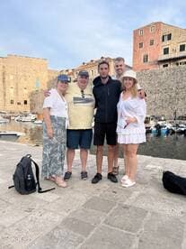 A cheerful group poses together at a picturesque harbor, capturing a memorable moment during their boating adventure.