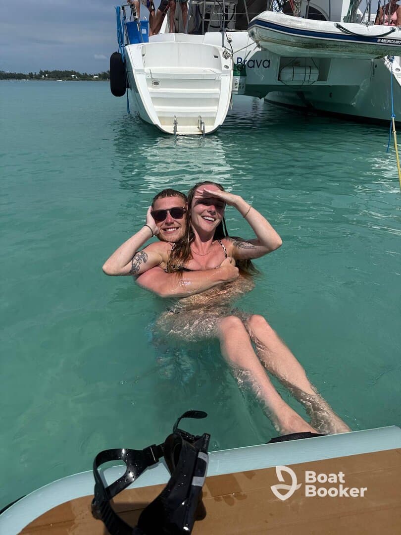 A couple enjoys a playful moment in the turquoise waters while relaxing near their boat, capturing the essence of fun and adventure on the water.