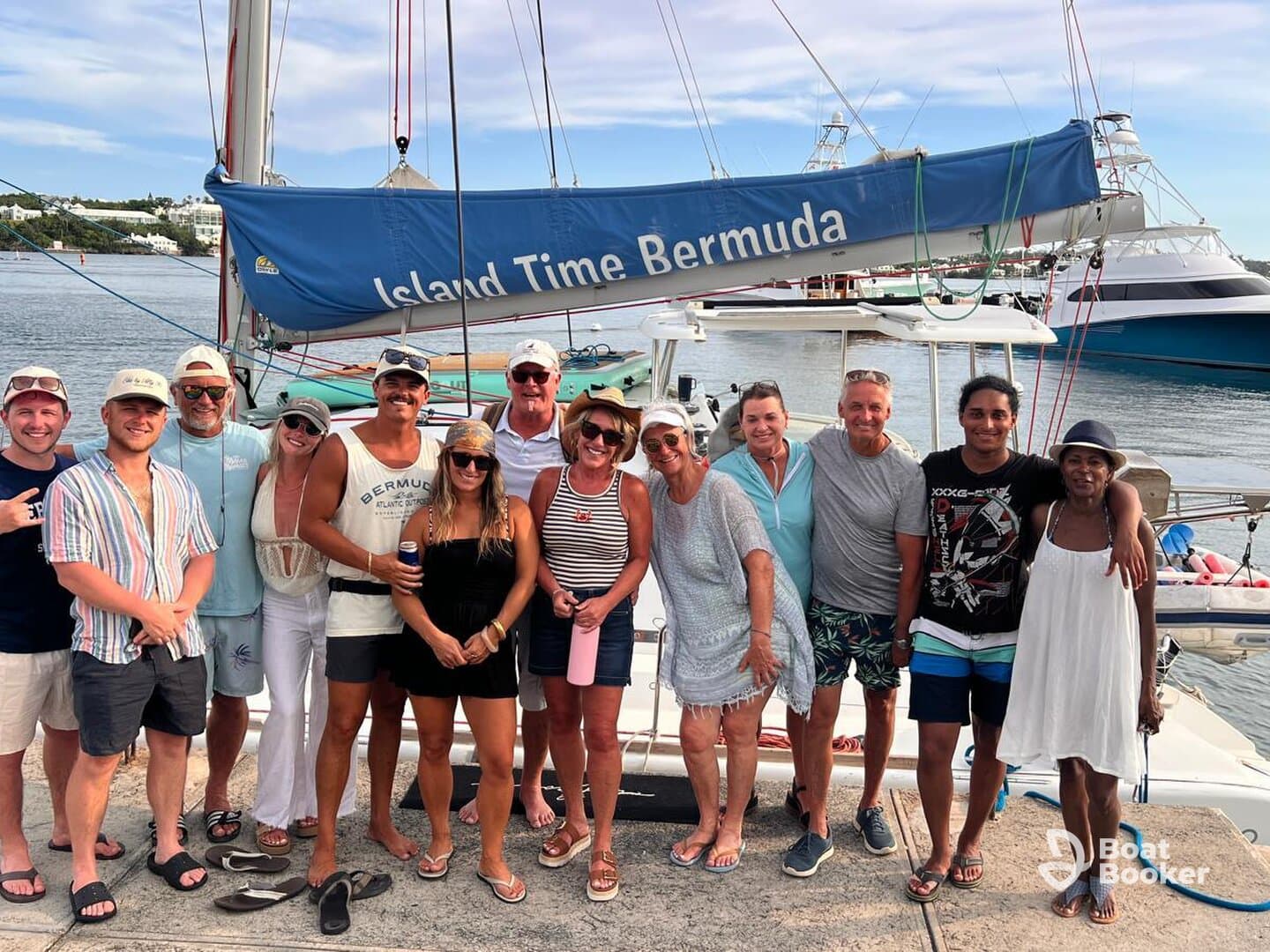 A cheerful group poses together in front of the 'Island Time' boat in Bermuda, capturing the spirit of adventure and camaraderie on their sailing trip.