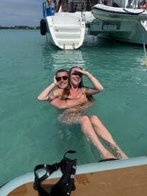 A couple enjoys a playful moment in the turquoise waters while relaxing near their boat, capturing the essence of fun and adventure on the water.