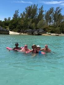 A cheerful group enjoys a refreshing swim in crystal-clear waters, perfect for a day of relaxation and fun at the beach.