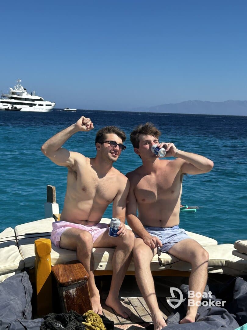 Two friends celebrate on the deck of a boat, enjoying drinks and the sunny weather — a perfect moment for a fun day on the water.