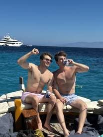 Two friends celebrate on the deck of a boat, enjoying drinks and the sunny weather — a perfect moment for a fun day on the water.
