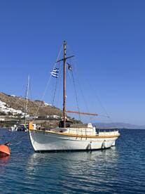 A picturesque sailboat docked in clear waters, showcasing its elegant design against a backdrop of a coastal village.