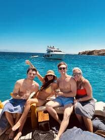 A lively group enjoys drinks and sunbathing on a yacht, capturing the essence of a perfect day on the water with friends.