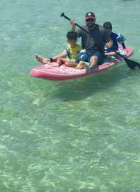 A family enjoys paddleboarding in clear waters, creating unforgettable memories on a sunny day.