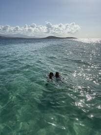 A couple enjoys a refreshing swim in crystal-clear waters, surrounded by stunning scenery — a perfect moment for a tropical getaway.