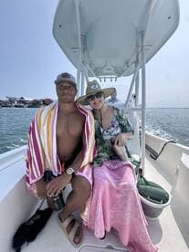 A couple enjoys a sunny day on a boat, wrapped in towels and relaxing together — perfect for a day of fun on the water.