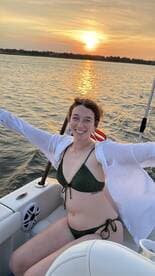 A joyful woman enjoys a sunset on the water, showcasing the perfect atmosphere for a relaxing boat trip.