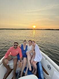 A group of friends enjoys a beautiful sunset on a boat, capturing the essence of summer fun and camaraderie on the water.