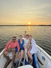 A joyful group of friends enjoys a sunset cruise on a boat, capturing the perfect moment of celebration and camaraderie on the water.
