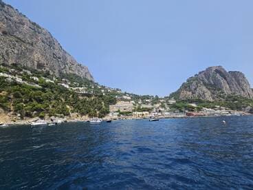 A stunning view of the coastline and harbor of Capri, showcasing the beautiful cliffs and vibrant buildings along the shore — a perfect destination for boat tours and scenic cruises.