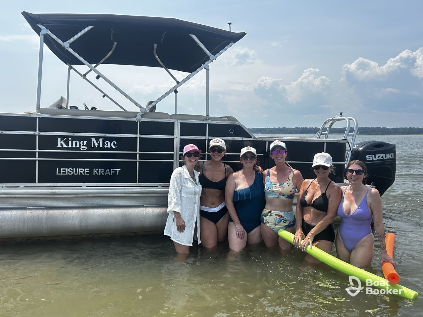 A fun group of friends enjoys a sunny day in the water next to their pontoon boat, 'King Mac,' perfect for summer gatherings and celebrations.